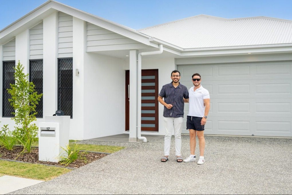 Modern beige house with a driveway, garage, and front yard landscaping.