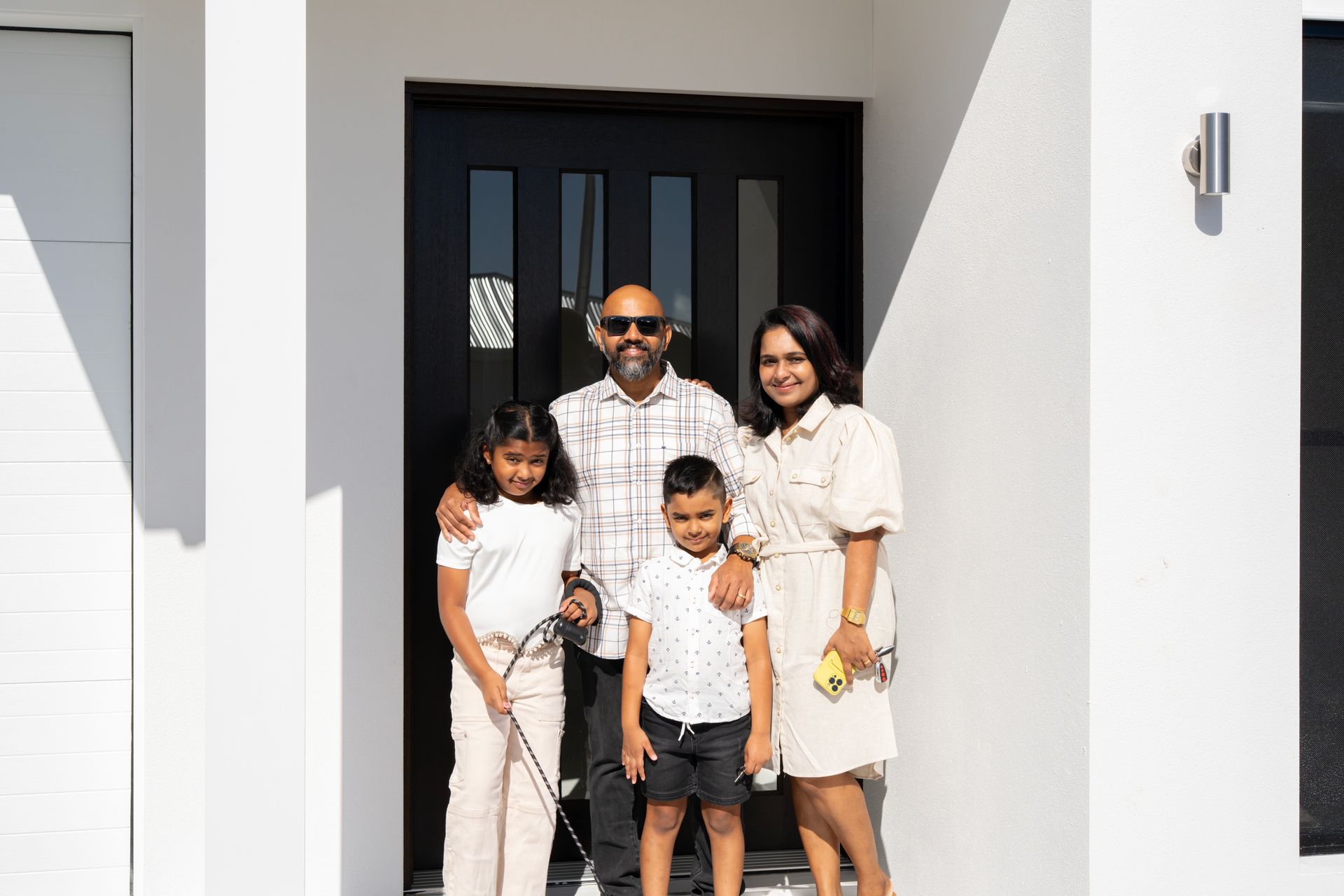 Single-story house with a white roof, gray siding, brown garage door, and a stone walkway.