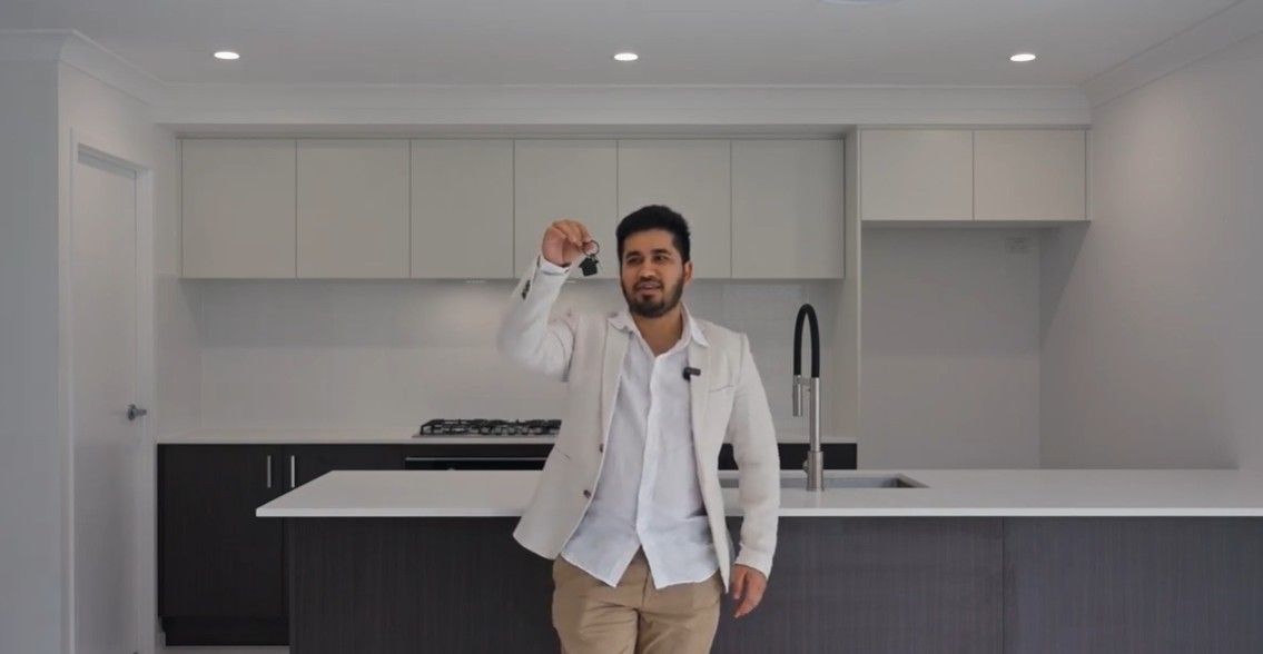 Modern beige house with a driveway, garage, and front yard landscaping.