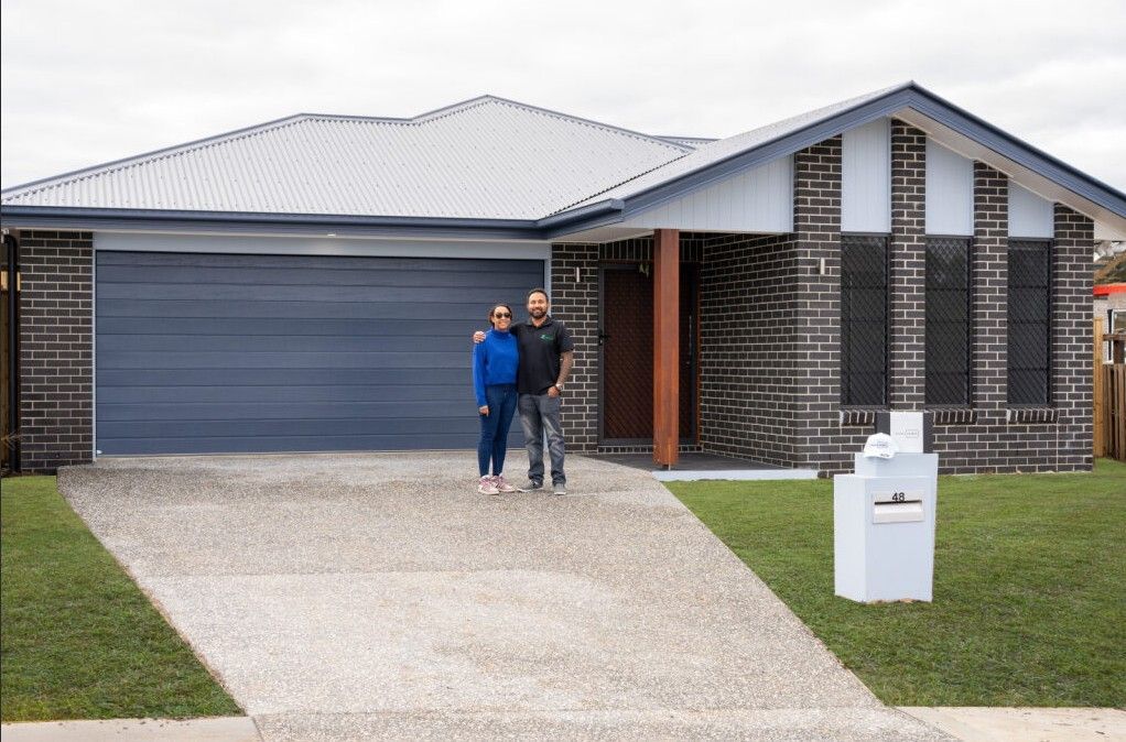Modern beige house with a driveway, garage, and front yard landscaping.