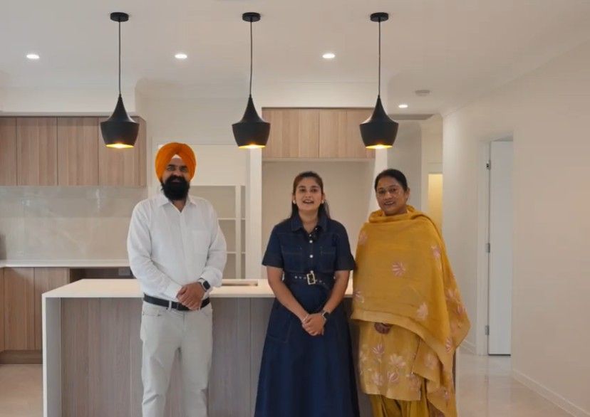 Single-story house with a white roof, gray siding, brown garage door, and a stone walkway.