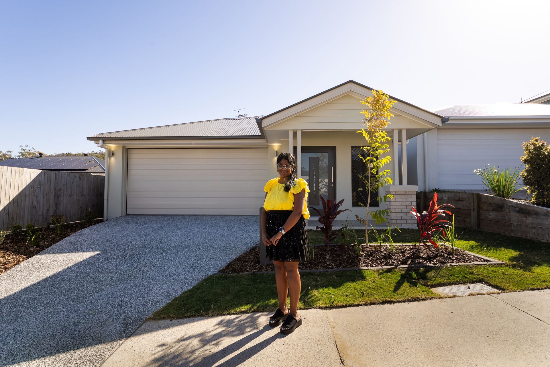 First home buyer standing in front of her newly built home in Brisbane