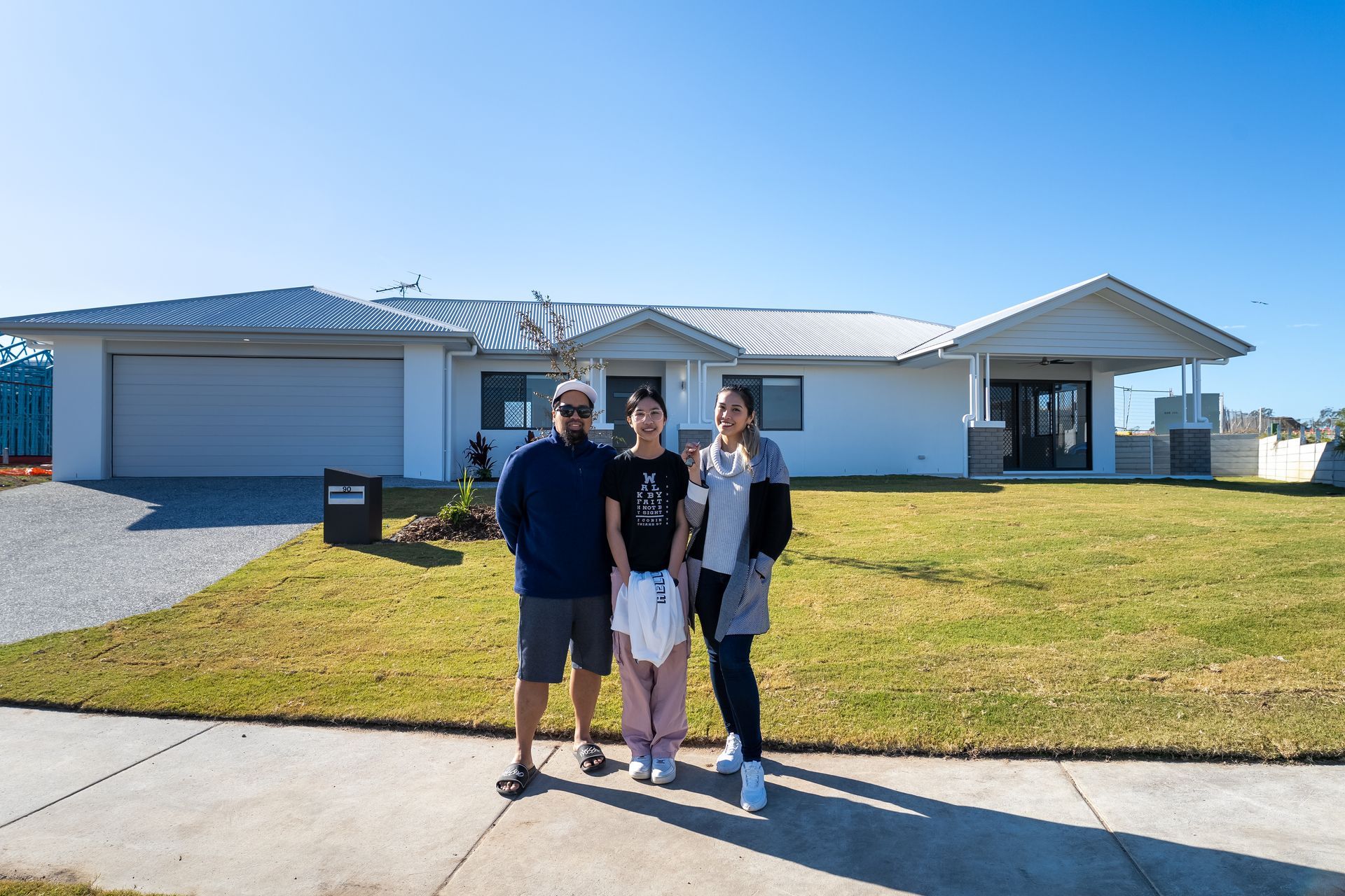 Single-story house with a white roof, gray siding, brown garage door, and a stone walkway.