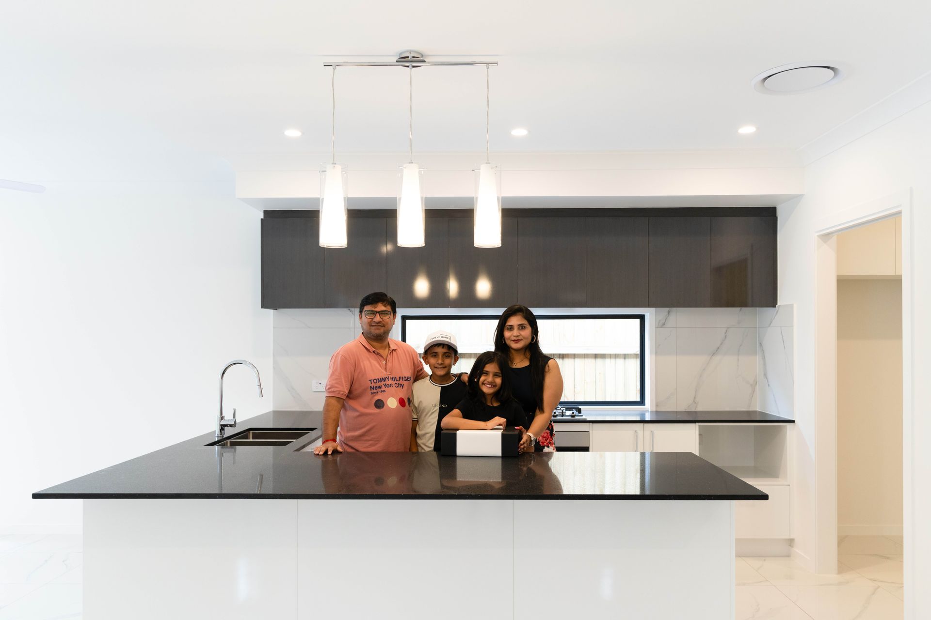 White suburban house with gray roof and garage door. Blue sky, green grass.