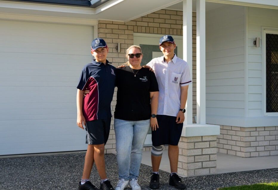 Single-story house with a white roof, gray siding, brown garage door, and a stone walkway.