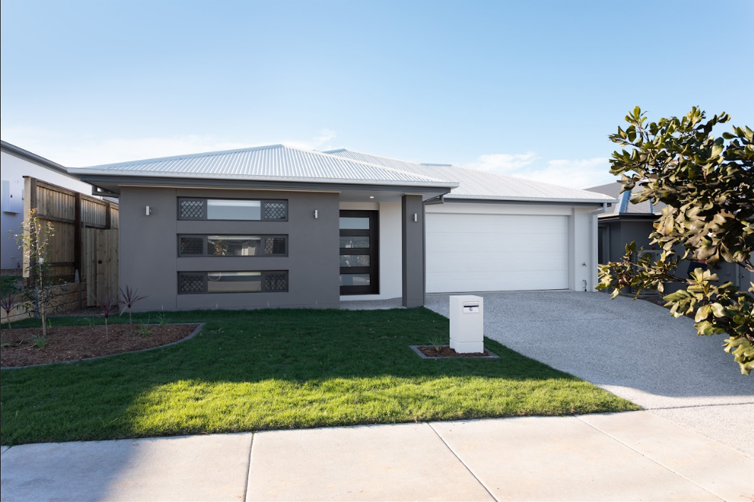 Modern gray house with white garage and driveway, green lawn, sunny day.
