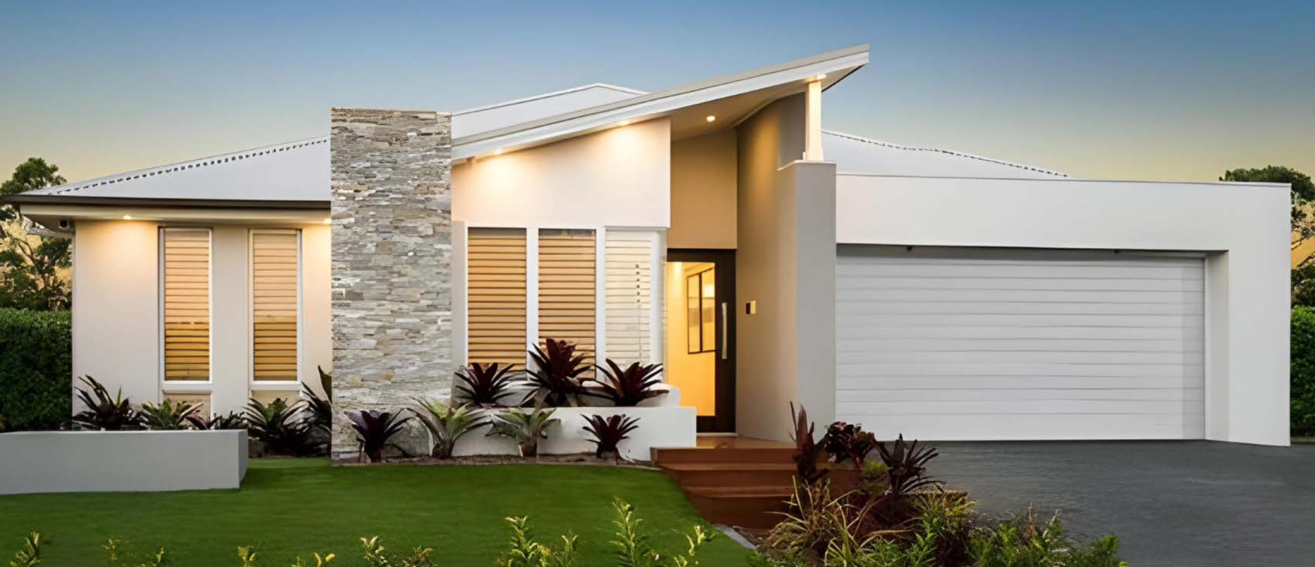 Modern, white house with gray stone accents and green lawn. Features a sloped roof and garage door.
