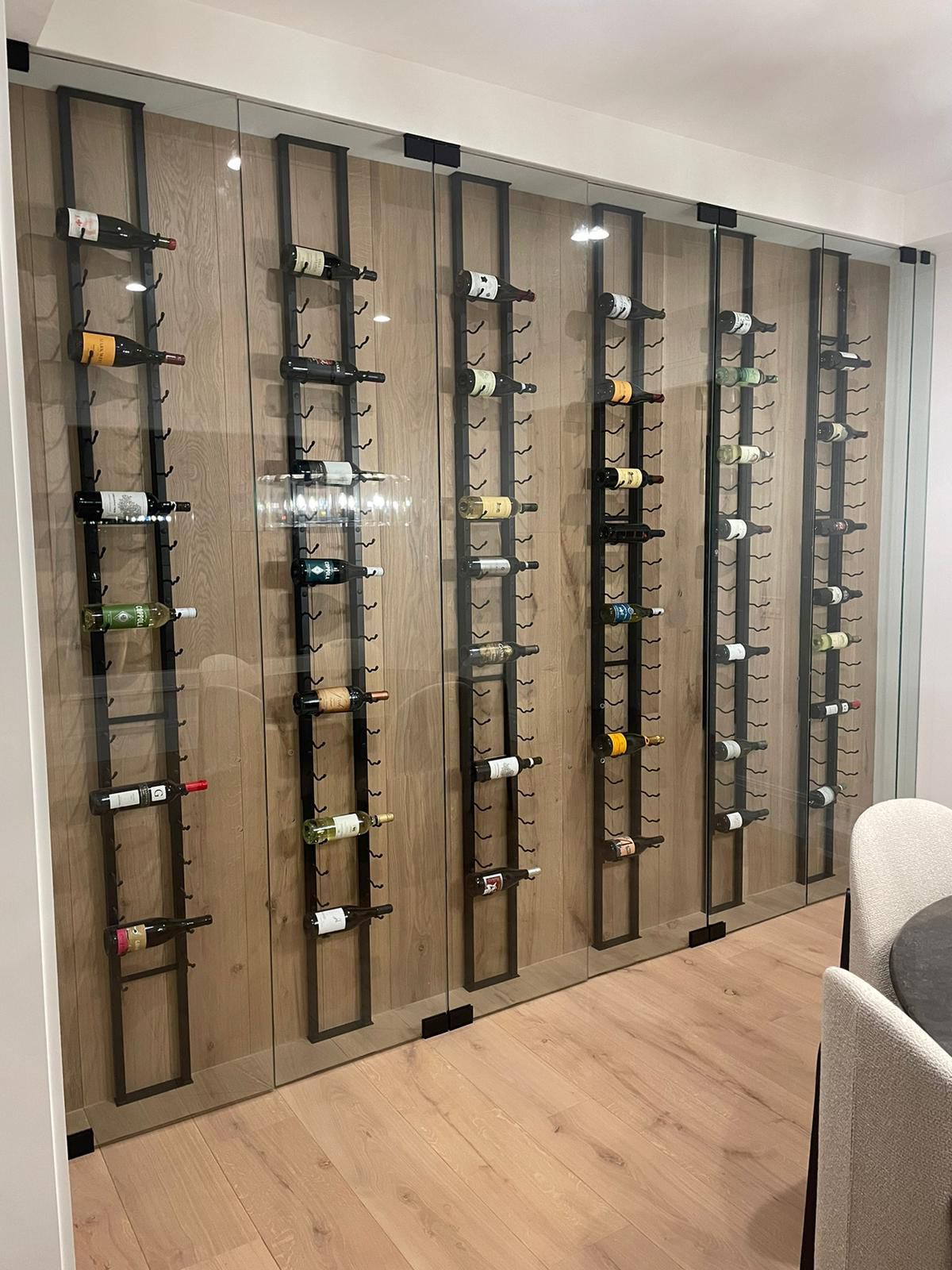 Elegant glass doors on a wine cellar, showcasing a collection of fine wines inside.