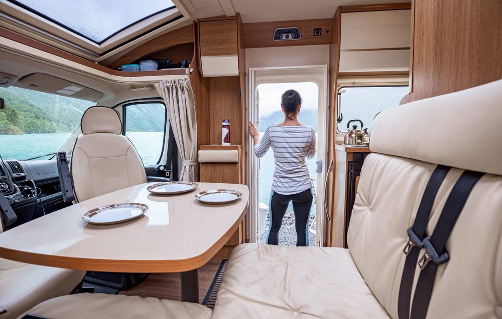A Woman is Standing in a Camper Van Looking Out the Door — Custom Unique Trimming in Mackay, QLD