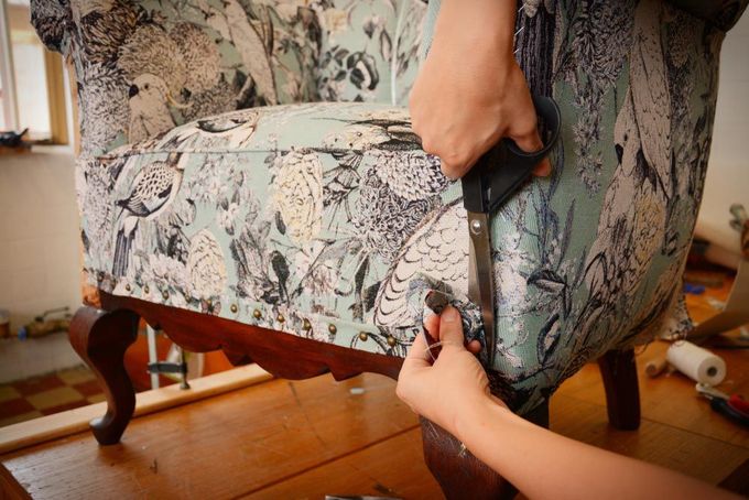 A Person is Cutting a Piece of Fabric on a Chair With Scissors — Custom Unique Trimming in Mackay, QLD