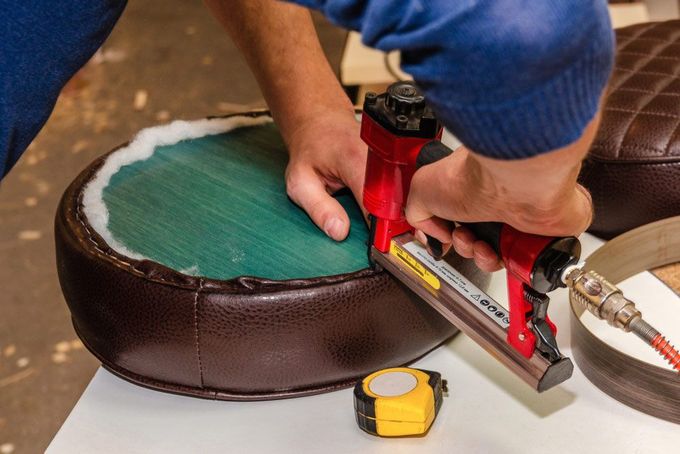 A Person is Using a Stapler to Fix a Chair Seat — Custom Unique Trimming in Mackay, QLD