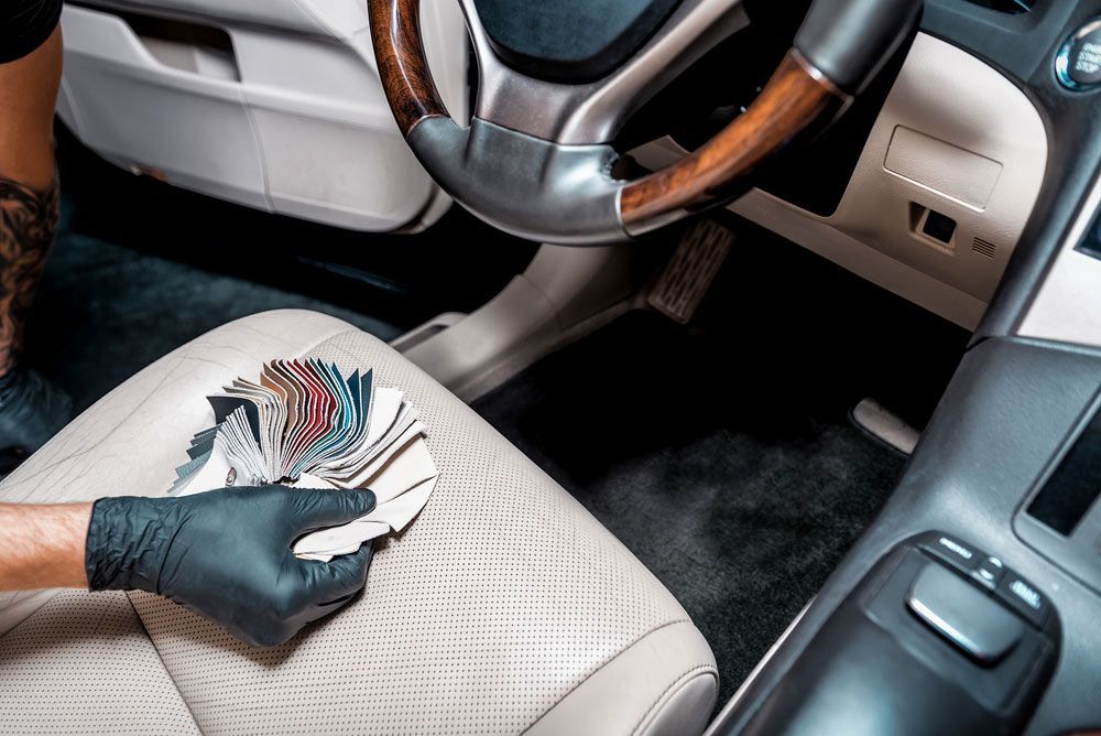 A Person Wearing Black Gloves is Cleaning the Seat of a Car — Custom Unique Trimming in Mackay, QLD