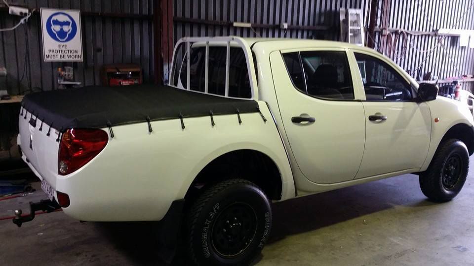 A White Truck With a Black Bed Cover is Parked in a Garage — Custom Unique Trimming in Mackay, QLD