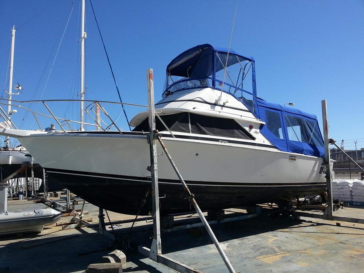 A White Boat With a Blue Canopy is Sitting on a Dock — Custom Unique Trimming in Mackay, QLD