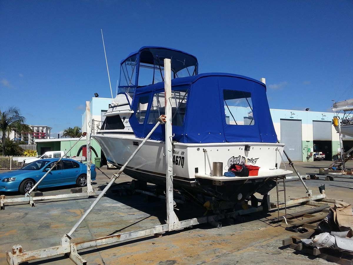 A Blue Car is Parked in Front of a Boat — Custom Unique Trimming in Mackay, QLD