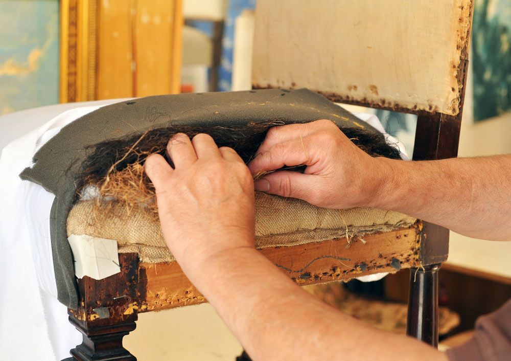 A Person is Fixing a Chair With Their Hands — Custom Unique Trimming in Mackay, QLD
