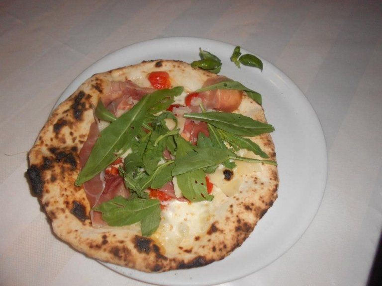 Una pizza con pomodori e verdure su un piatto bianco