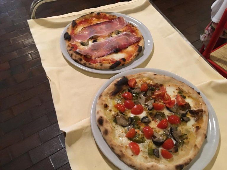 Su un tavolo ci sono due pizze con condimenti diversi