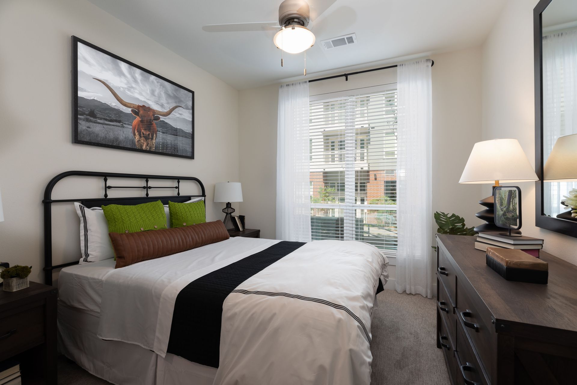 A bedroom with a bed , dresser , mirror and ceiling fan.