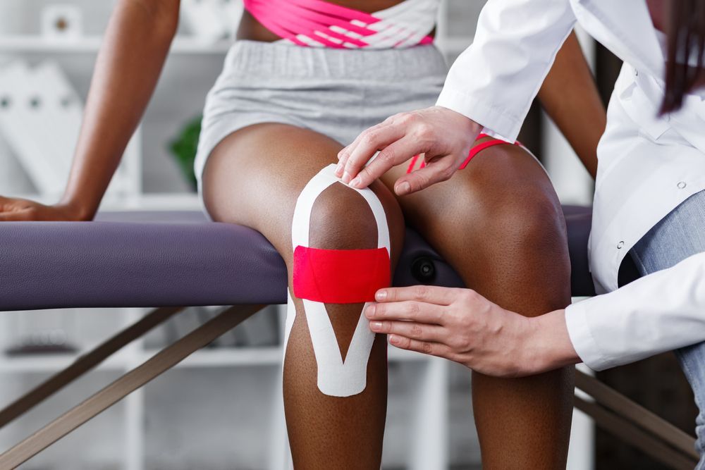 Person receiving kinesiology tape on knee by healthcare worker. — Bourbong Street Physiotherapy Centre in Bundaberg West, QLD