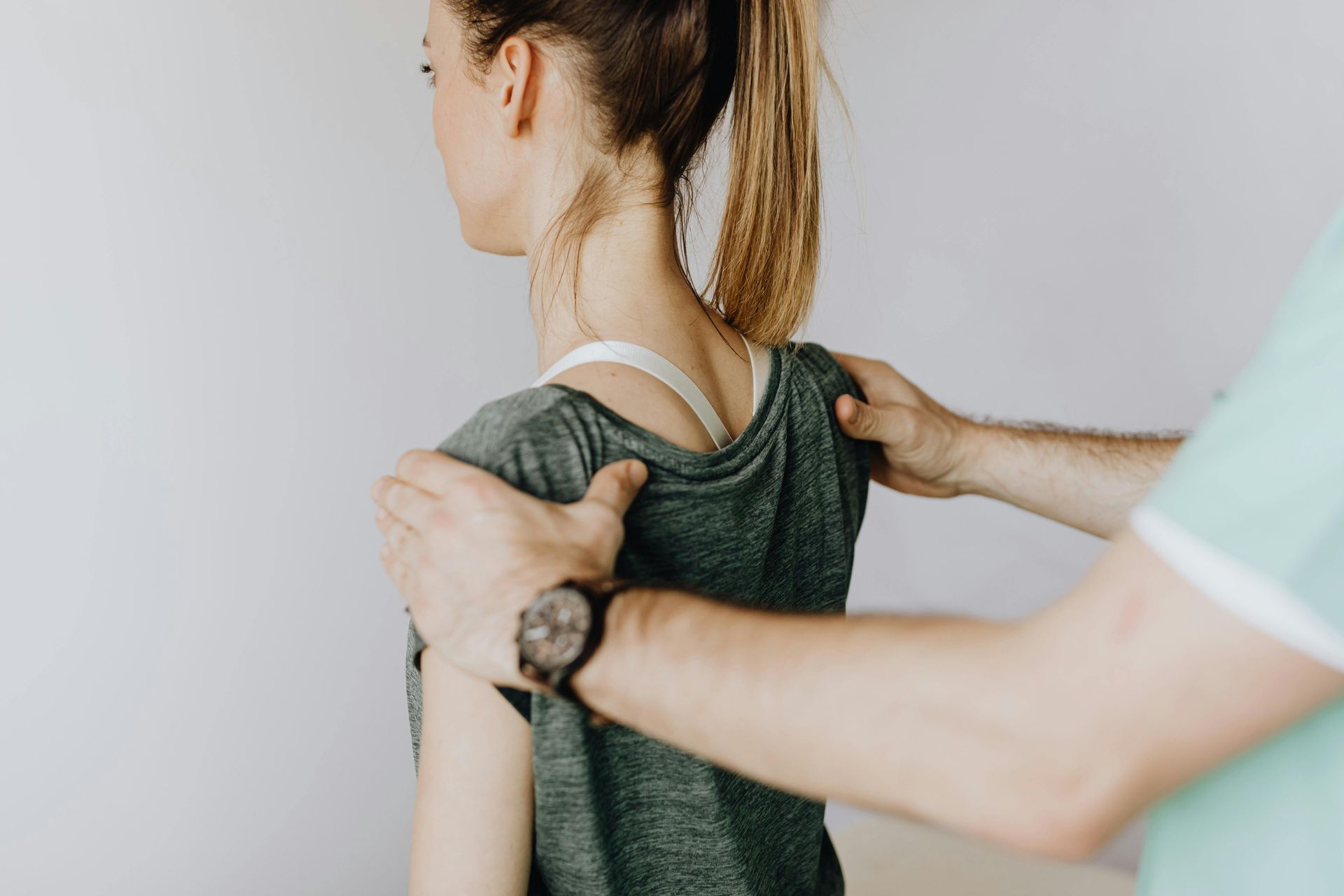 Person in green shirt having shoulders examined by a person in a mint green shirt; indoors. — Bourbong Street Physiotherapy Centre in Bundaberg West, QLD