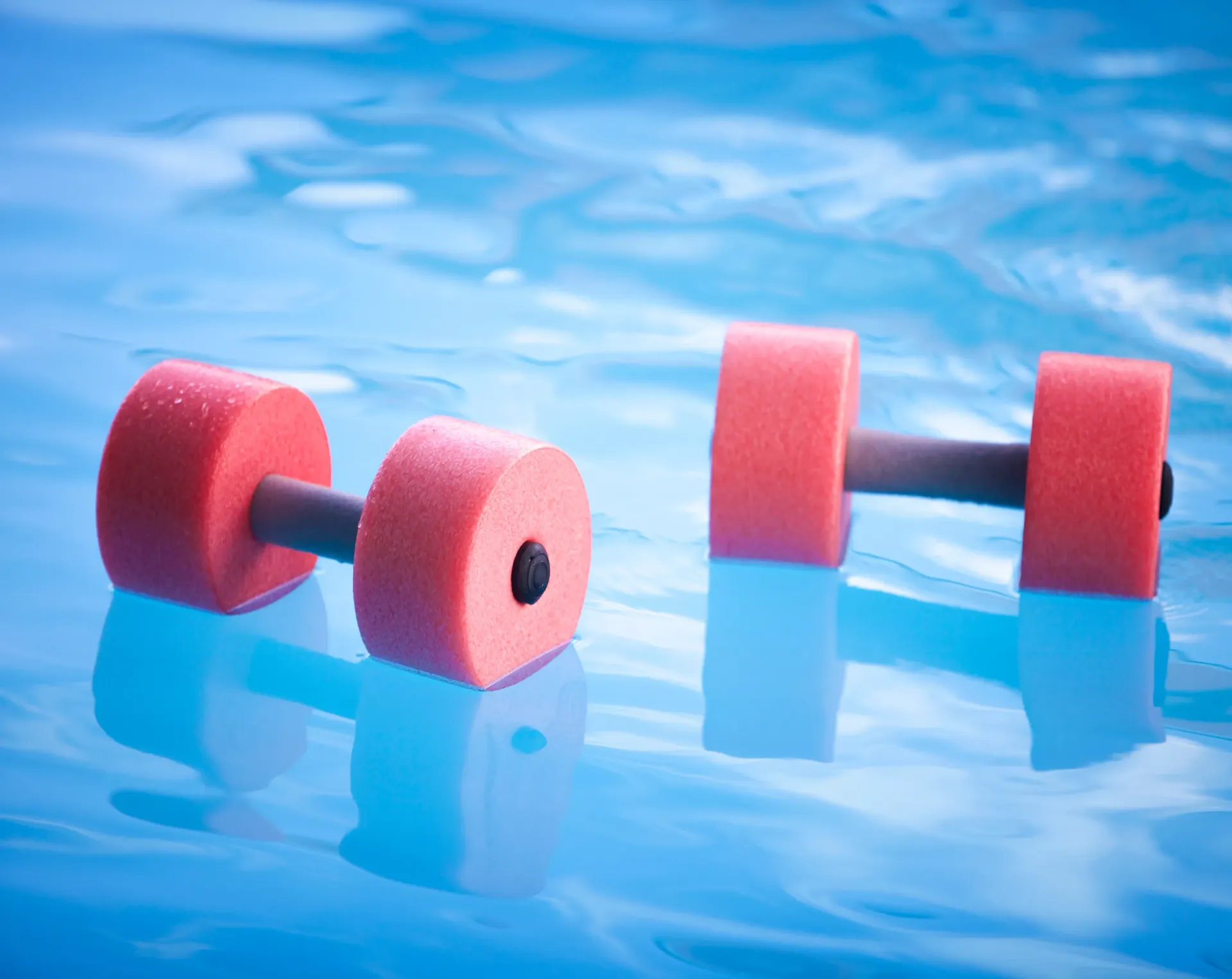 Two red and black water dumbbells floating in blue water. — Bourbong Street Physiotherapy Centre in Bundaberg West, QLD