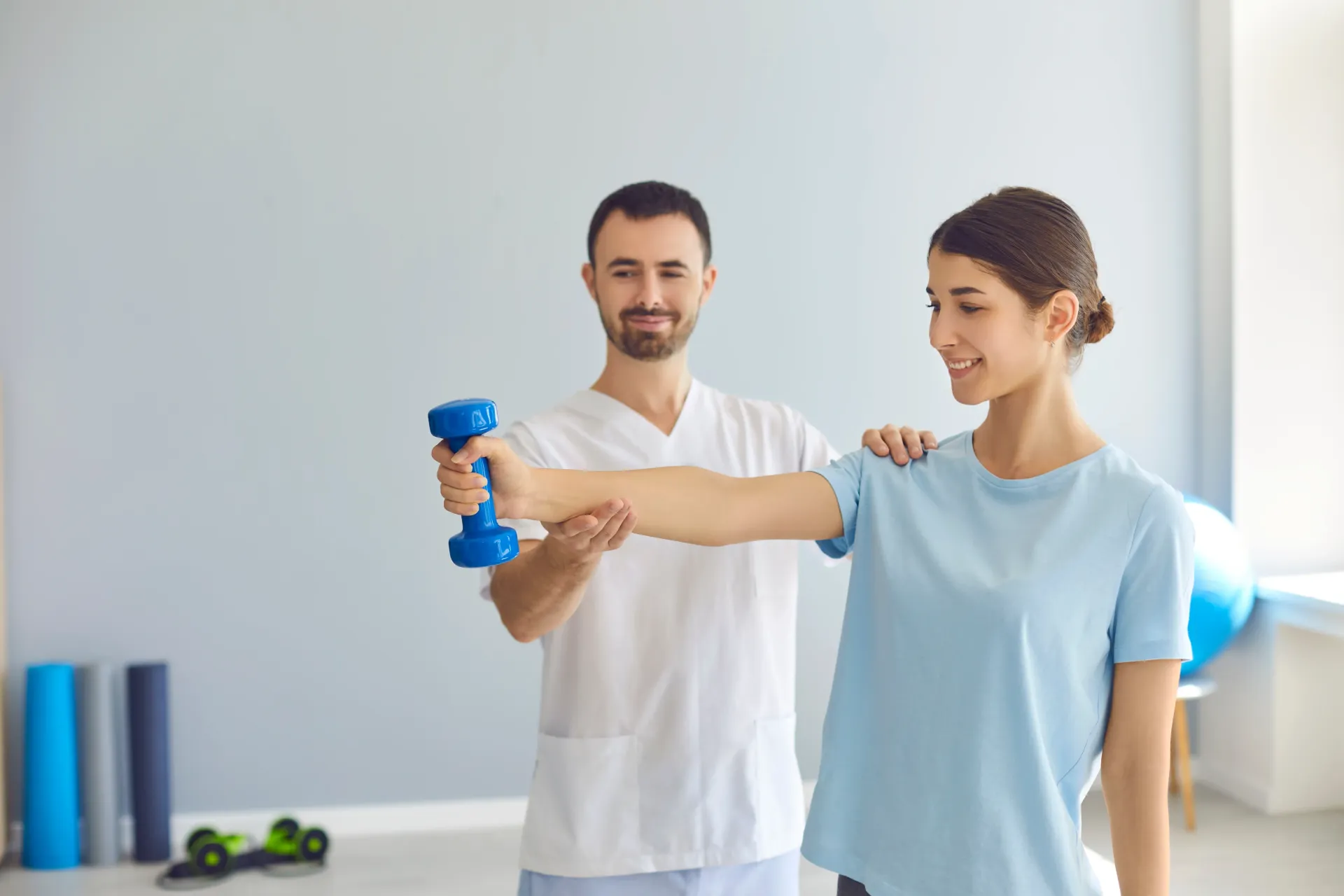 A physical therapist assists a patient with a dumbbell exercise in a clinic. — Bourbong Street Physiotherapy Centre in Bundaberg West, QLD
