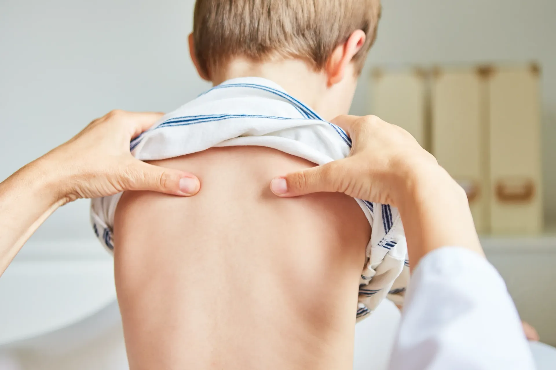 Doctor examines a child's back, gently pressing with hands. The setting appears to be a doctor's office. — Bourbong Street Physiotherapy Centre in Bundaberg West, QLD