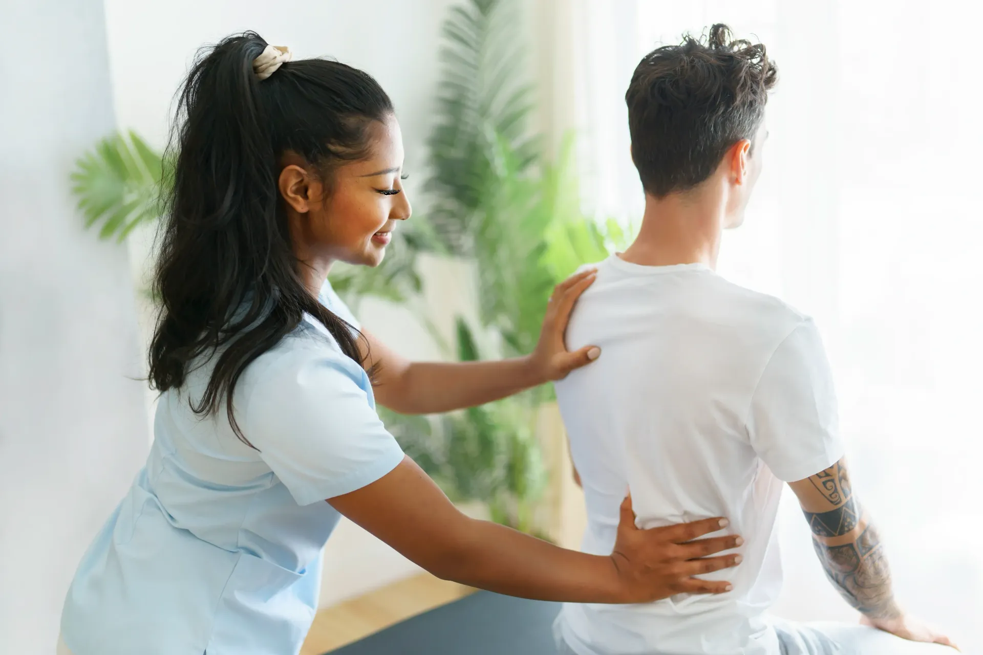 Physical therapist assisting a patient with back pain; hands on back. Indoor setting, white shirt. — Bourbong Street Physiotherapy Centre in Bundaberg West, QLD