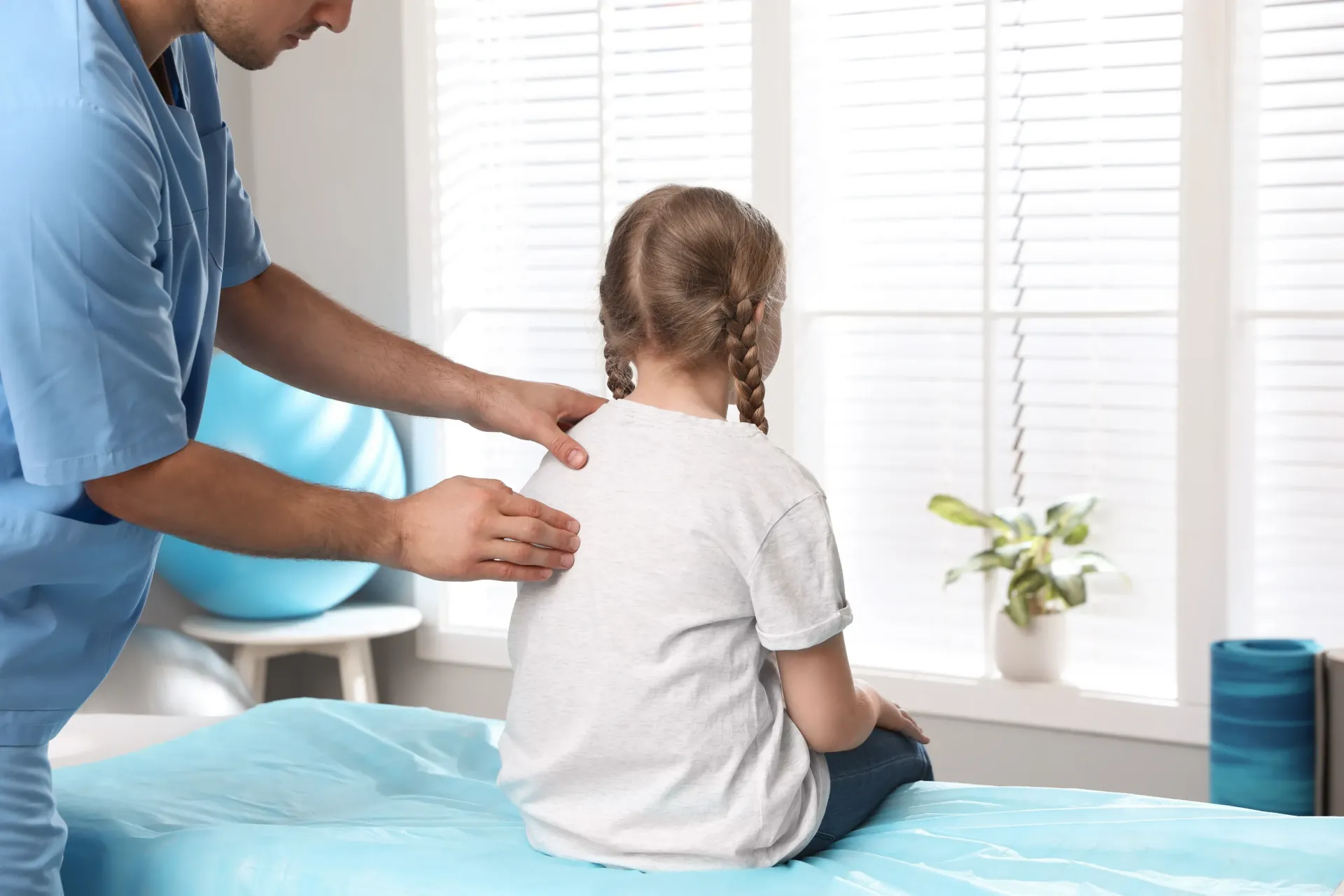 A healthcare professional examining a child's back in a clinic setting — Bourbong Street Physiotherapy Centre in Bundaberg West, QLD