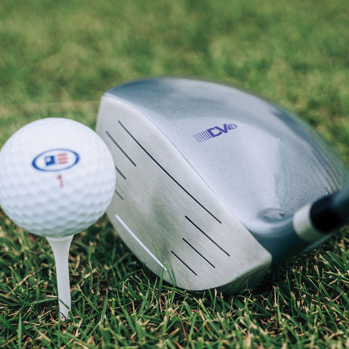 A golf ball on a tee next to a golf club