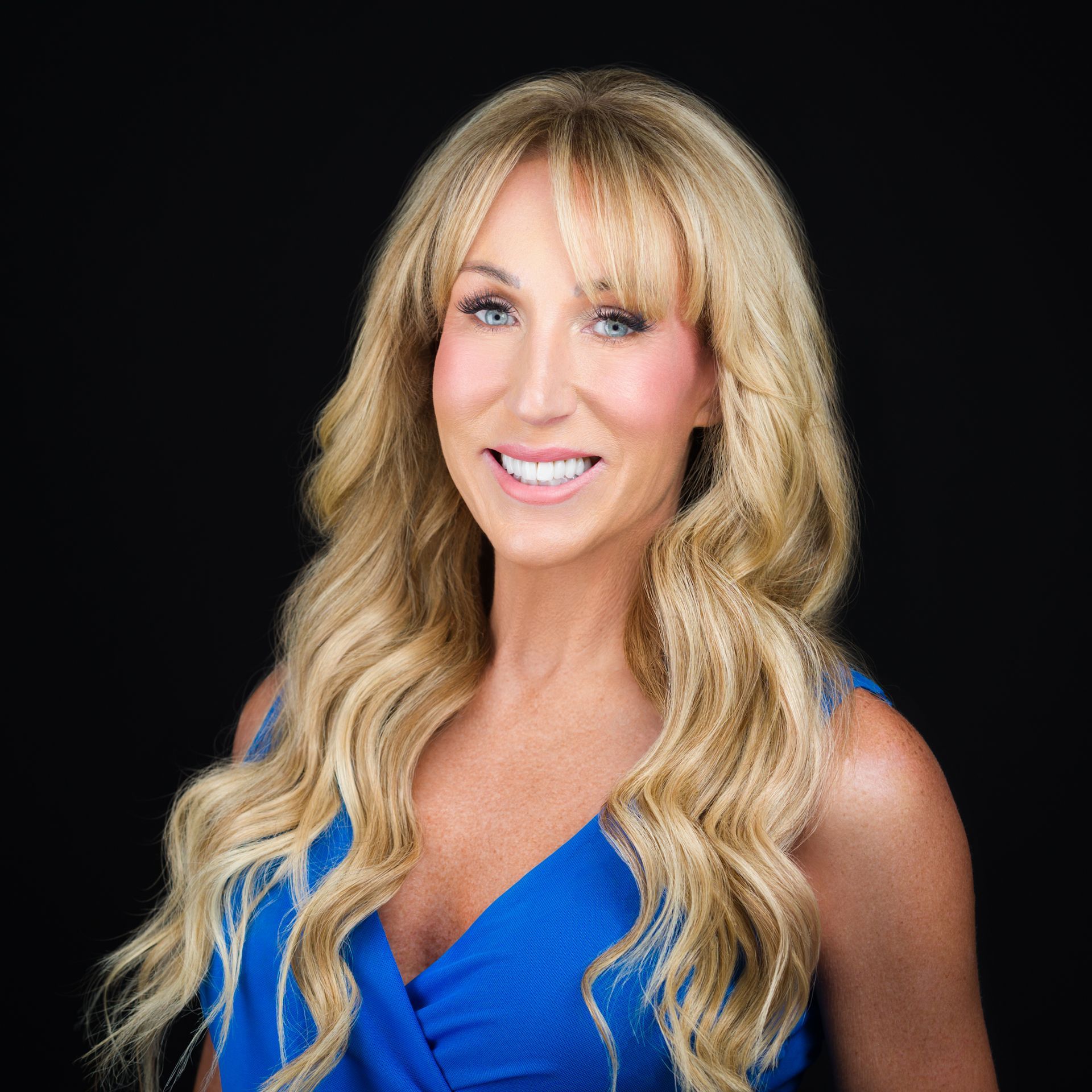 The woman is wearing a blue dress and smiling for the camera.