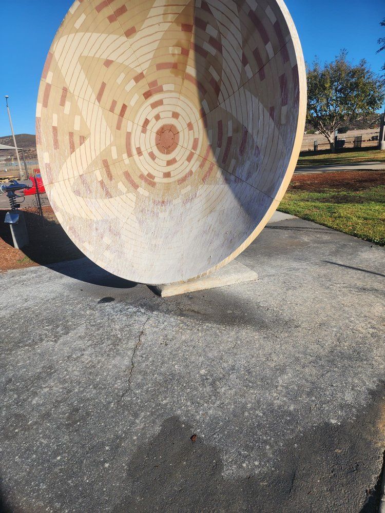 A large circular sculpture is sitting on a sidewalk in a park