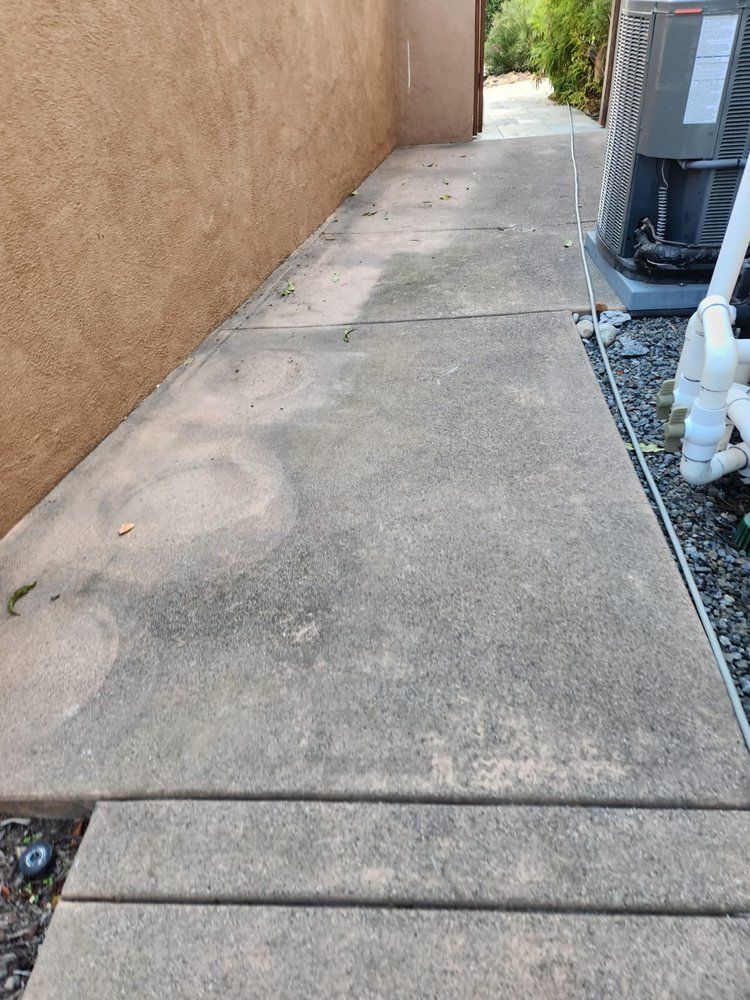 A concrete walkway next to a building with a heater on it.