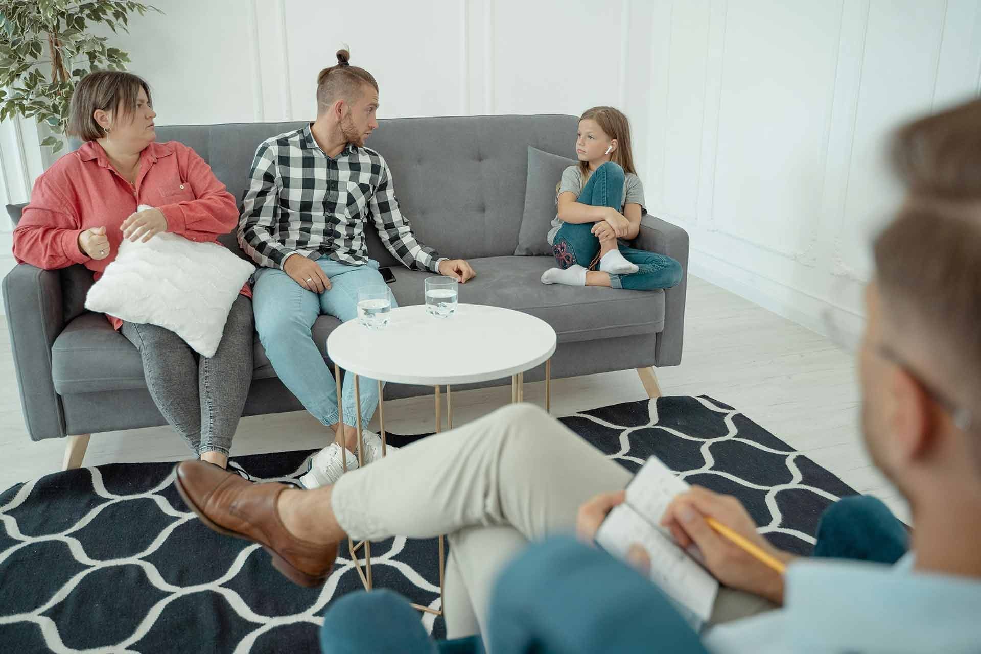 Therapist talking with a couple and child in a living room during a family counseling session