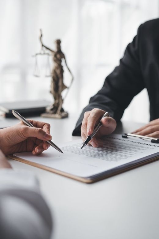 A man and a woman are sitting at a table signing a document.