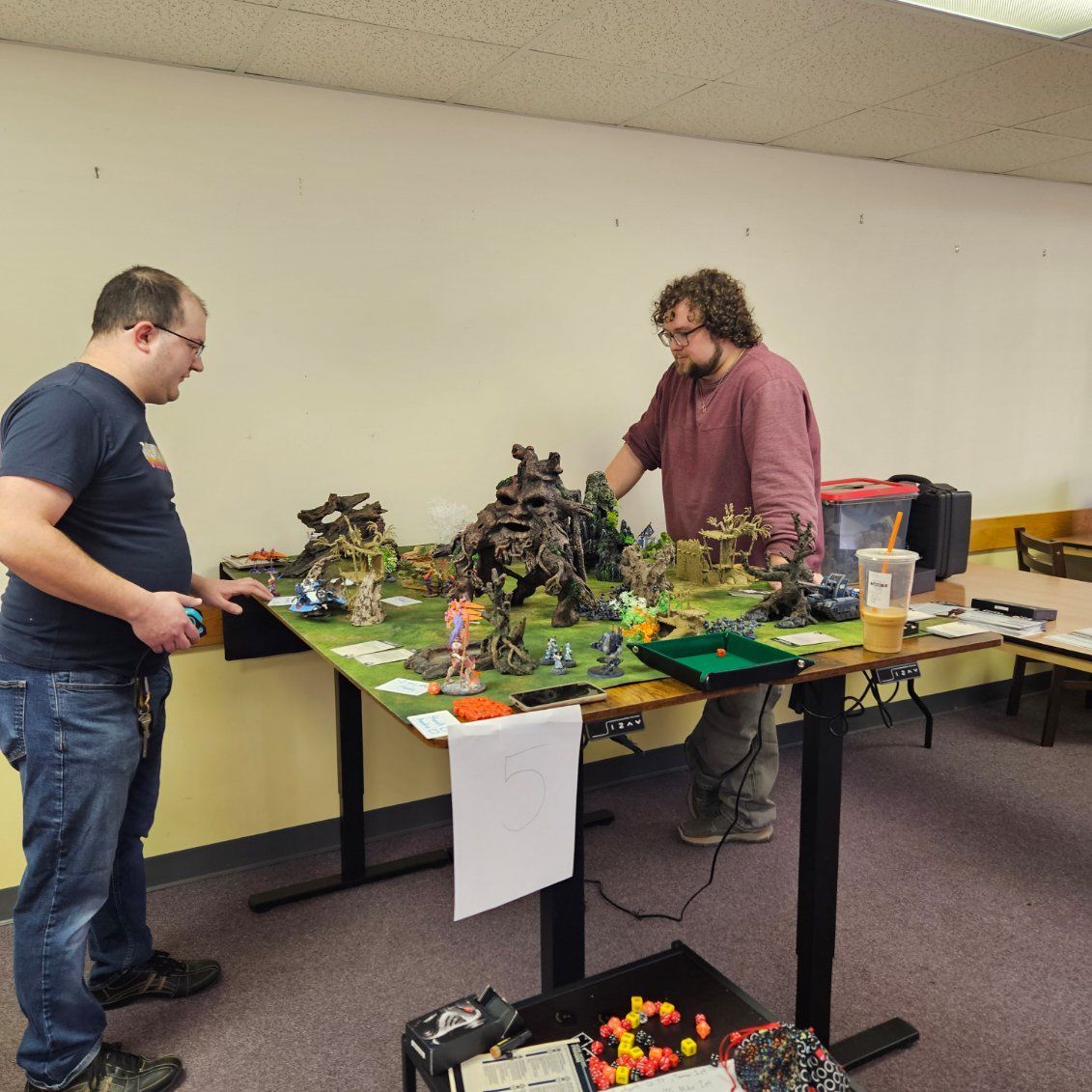 Two men are standing around a table with toys on it