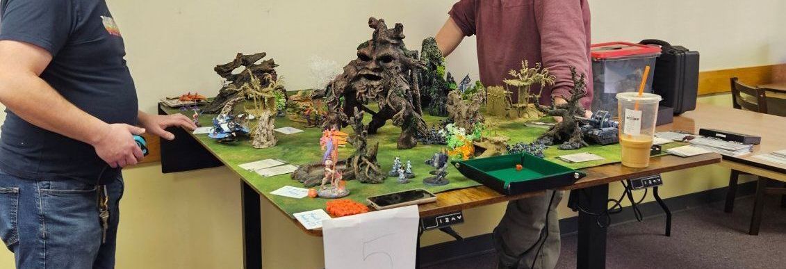 Two men are standing next to a table with a lot of toys on it.