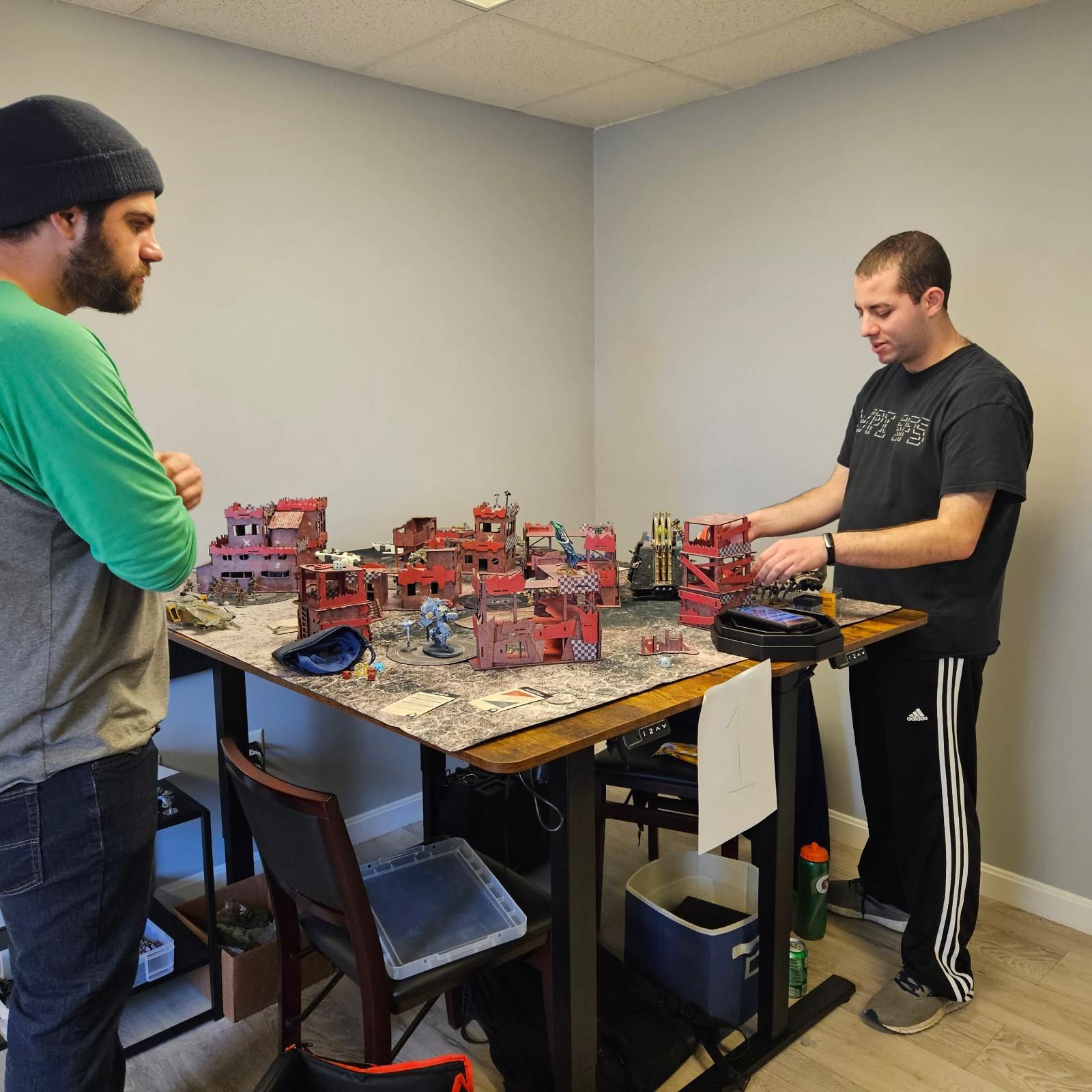Two men are standing in front of a table with miniature buildings on it