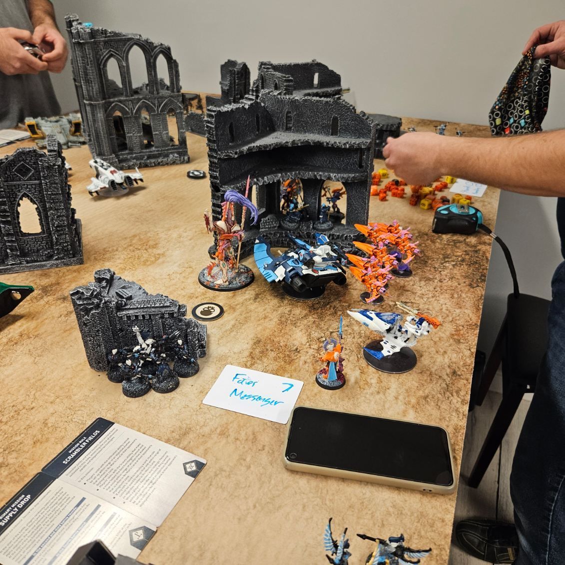 A group of people are playing a game of warhammer on a table.