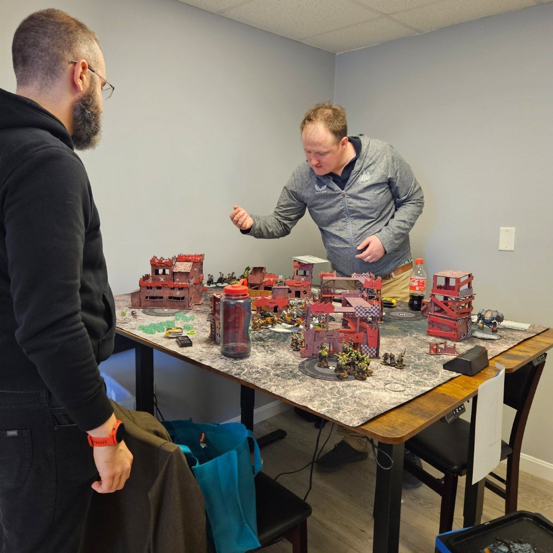 Two men are playing a game of warhammer on a table.