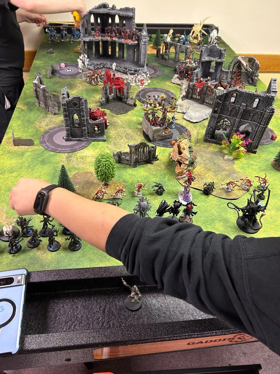 A person is playing a game with miniature figures on a table.