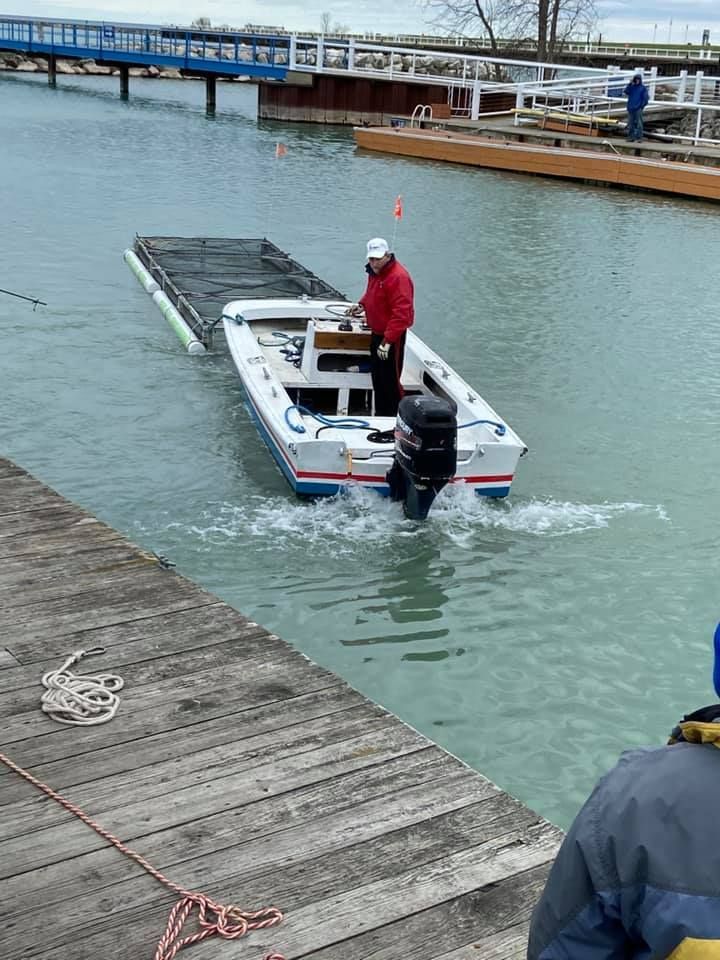 A man in a red jacket is pushing a boat into the water.