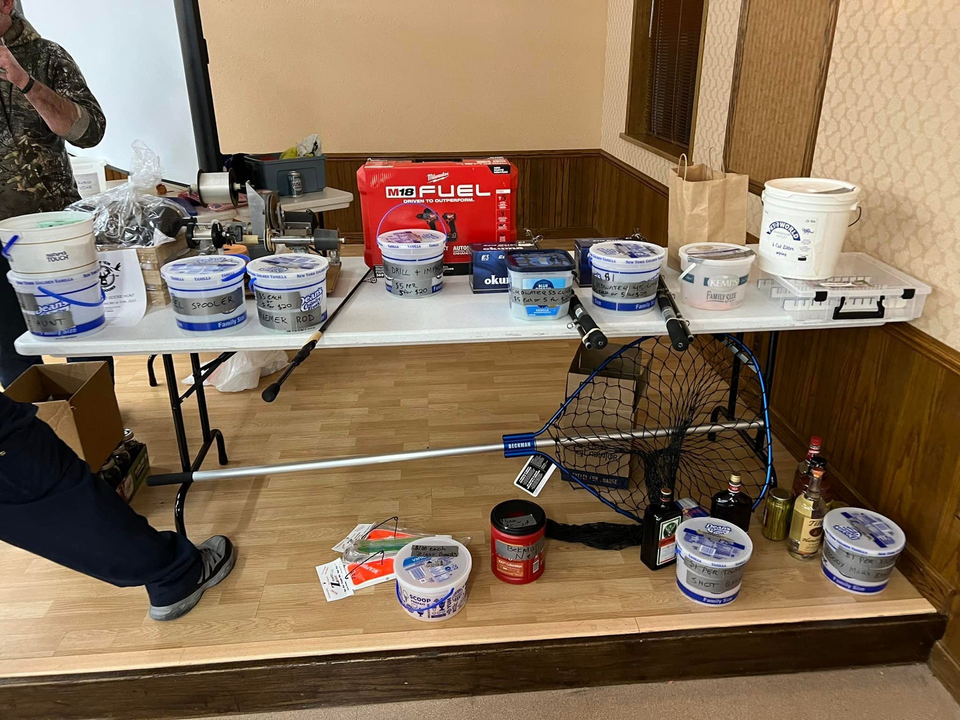 A man is standing in front of a table filled with fishing equipment.