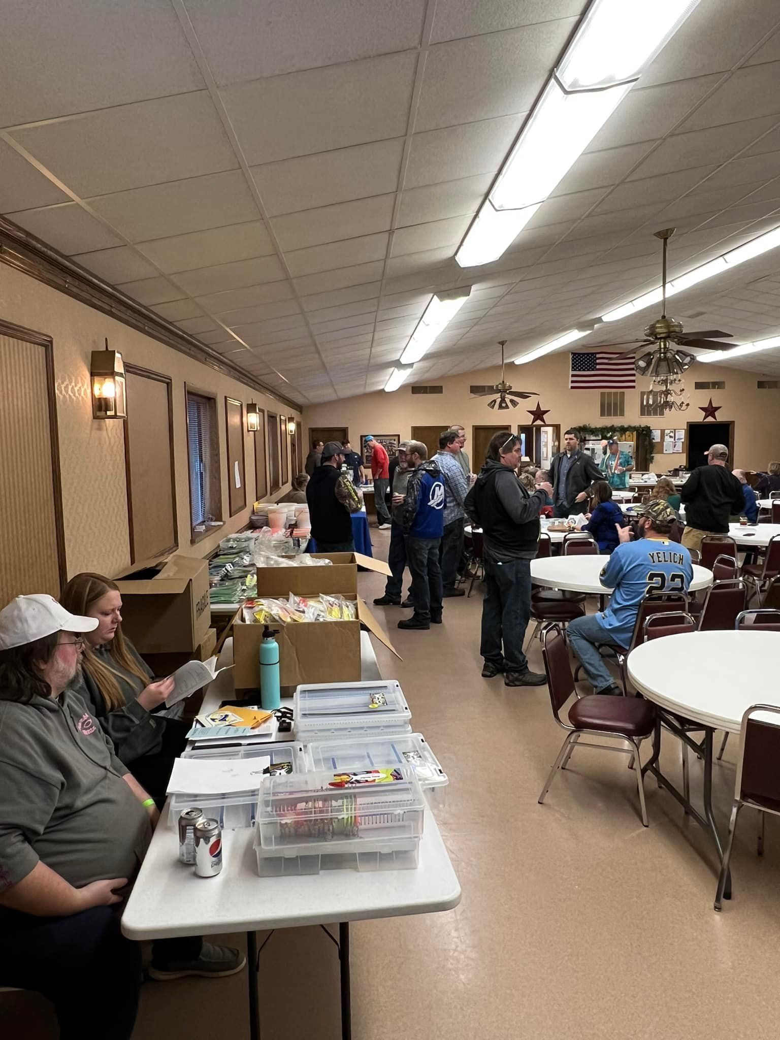 A group of people are standing around tables in a large room.