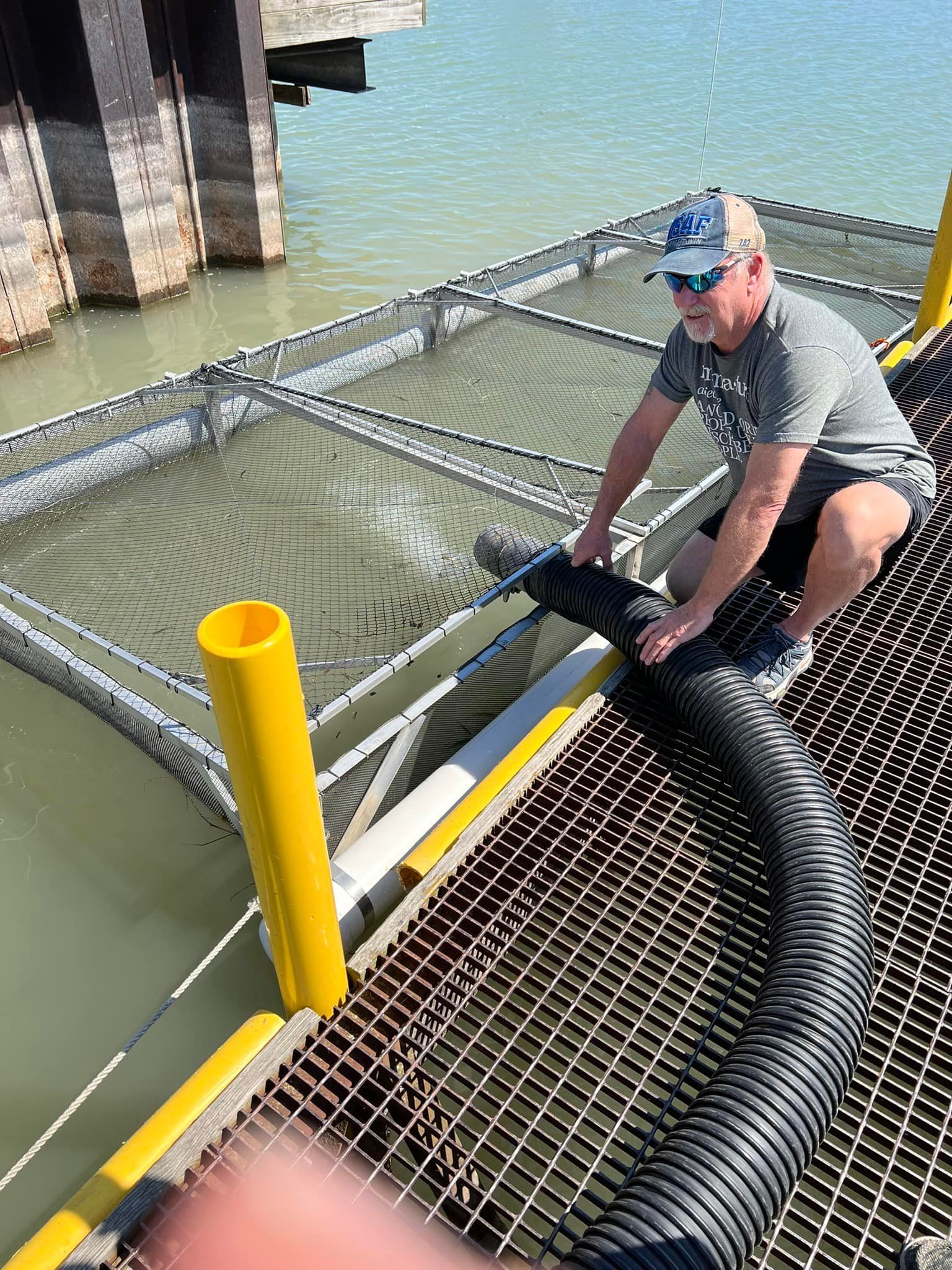 A man is using a vacuum hose to pump water into a cage.