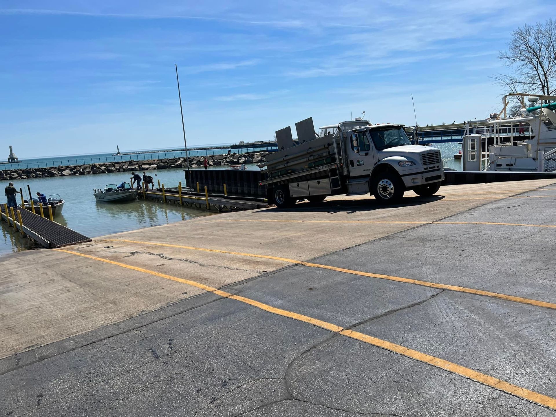 A white truck is parked in a parking lot next to a body of water.