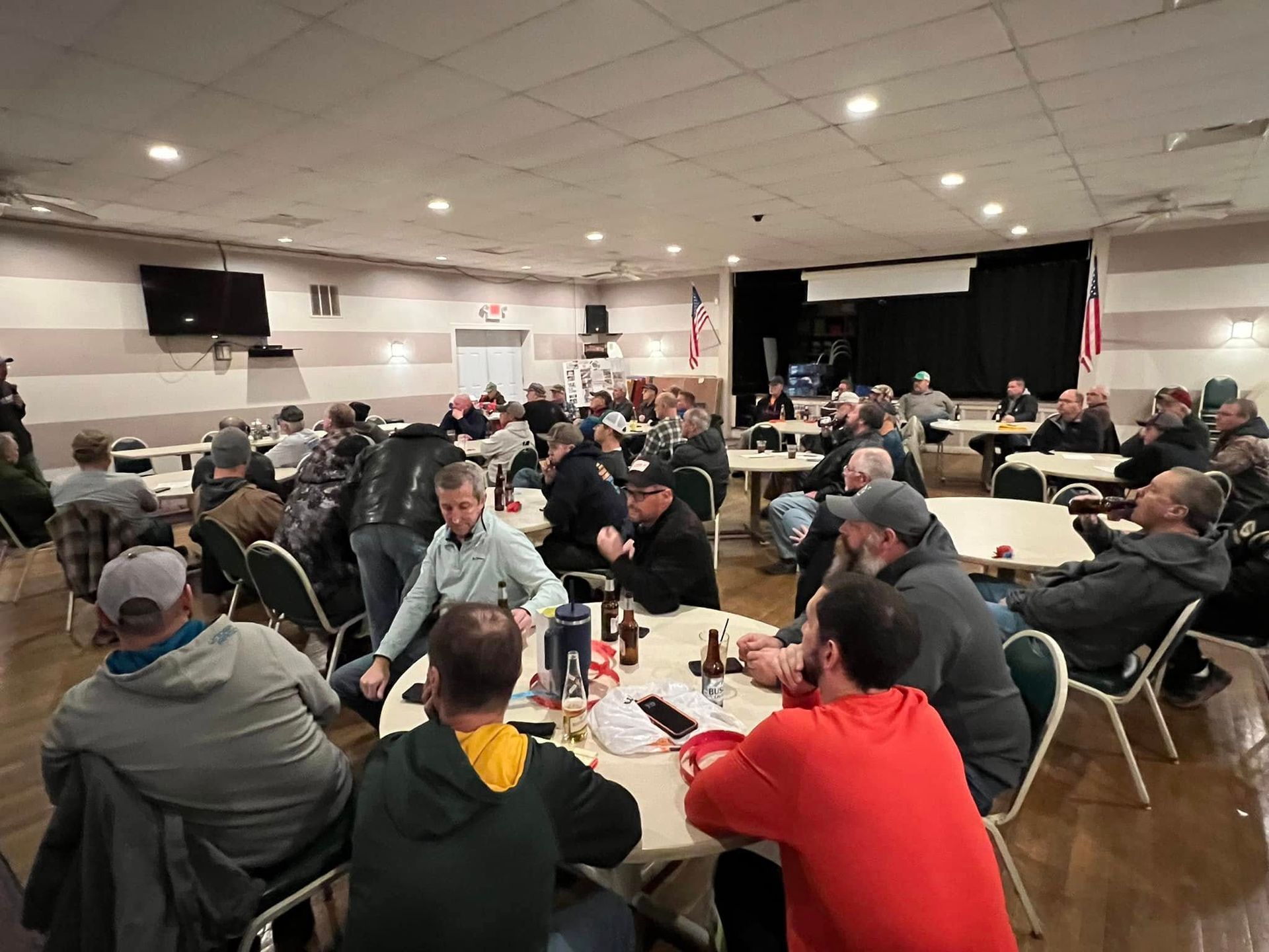 A large group of men are sitting at tables in a large room.