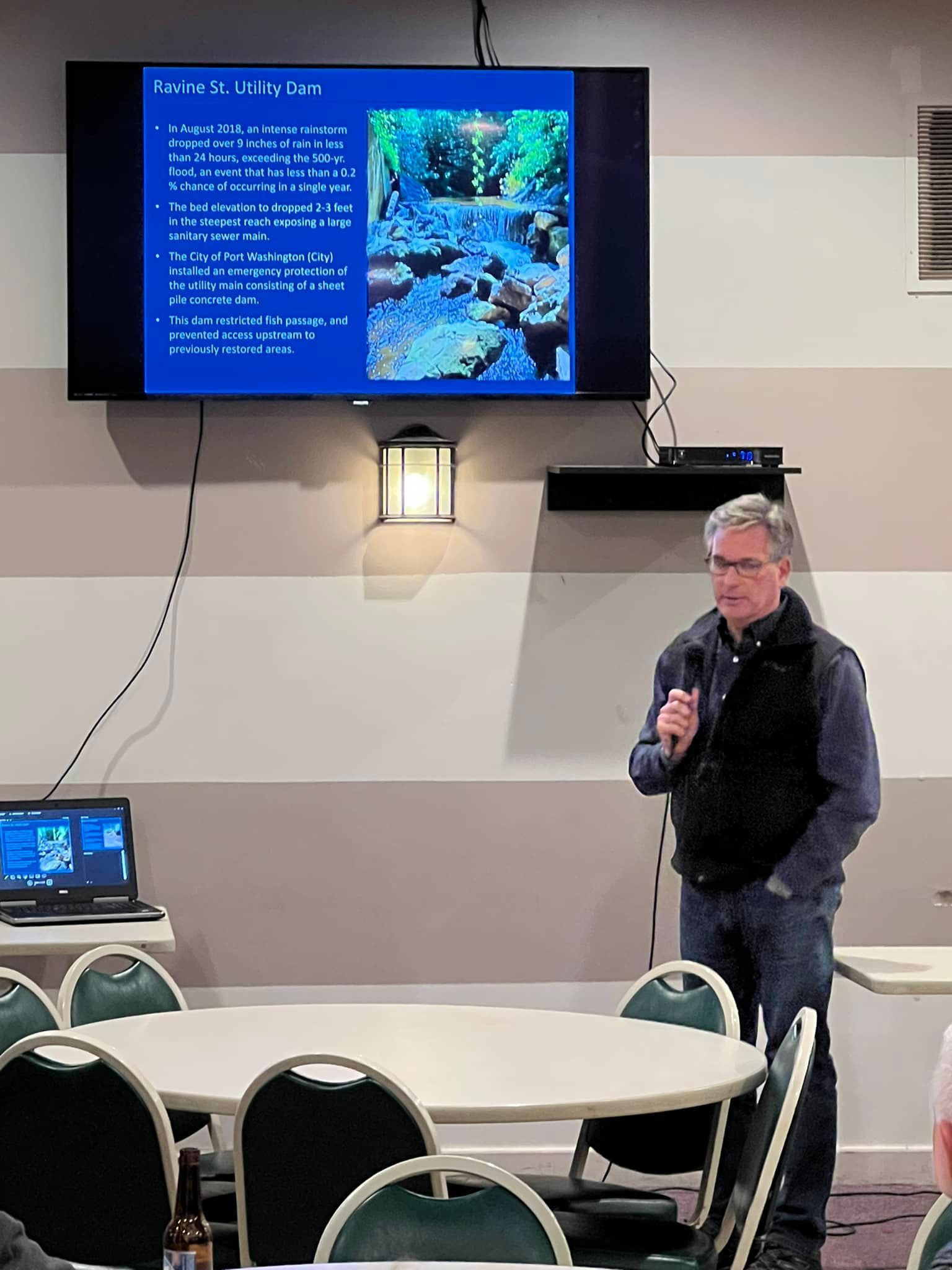 A man is giving a presentation in front of a large screen