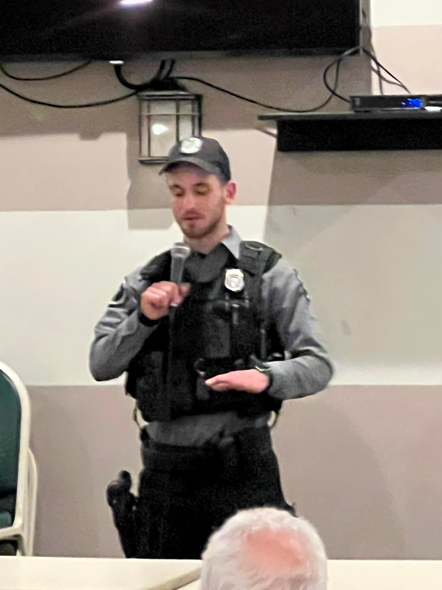 A police officer is standing in front of a microphone.